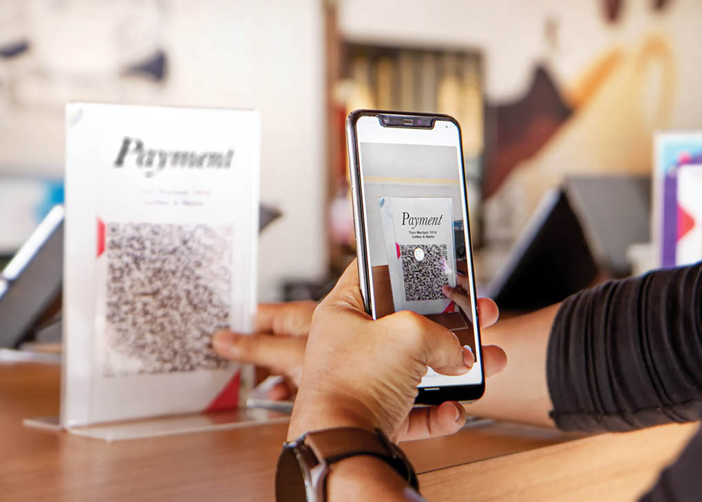 Customer using phone for payment at cafe restaurant, cashless QR code technology and money transfer concept